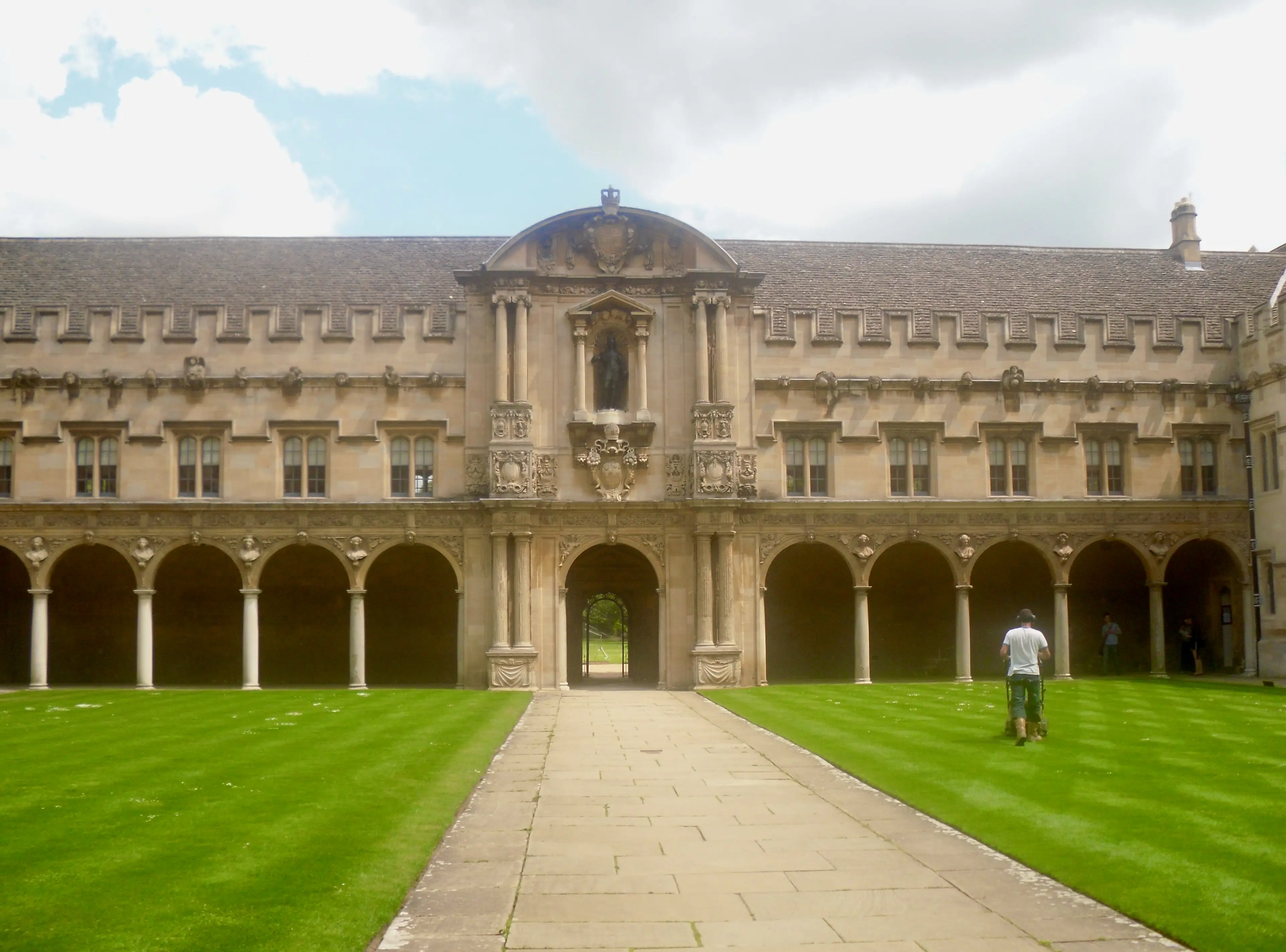 Canterbury Quad seen across its lawn, arcades on either side and a carved pediment above the far archway.