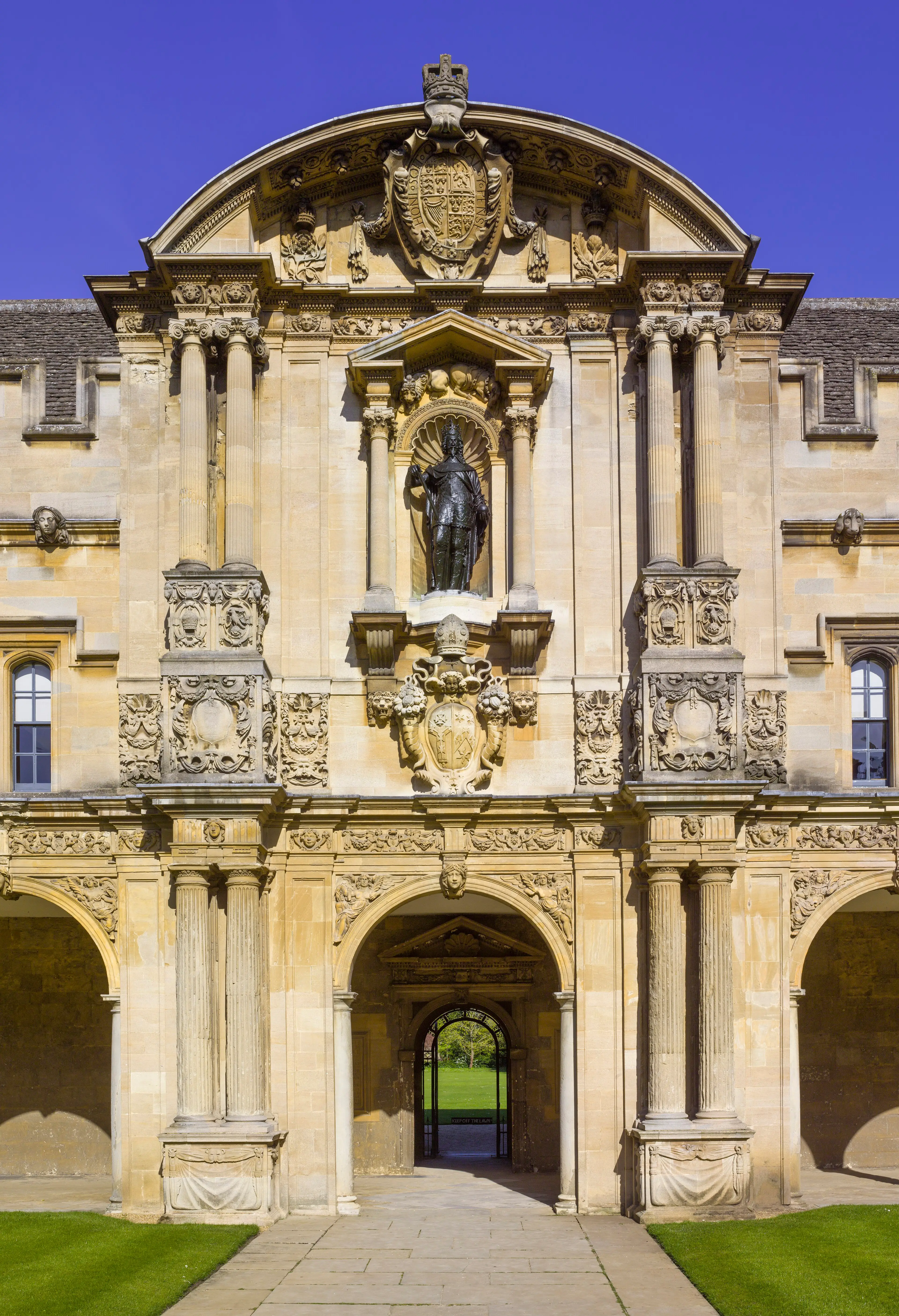 A stone archway on Canterbury Quad, carved with scrollwork and shields, seen through to the quad beyond.